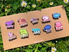 a bunch of pins sitting on top of a piece of cardboard next to some daisies