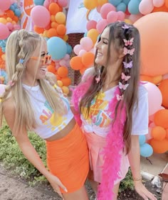 two young women standing next to each other in front of balloons