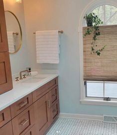 a bathroom with two sinks and a large window in the corner that has roman shades on it