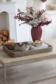 a tray with flowers and candles on top of a table in front of a fireplace