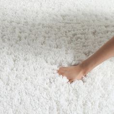 a woman's bare feet on a white fluffy area rug with her foot in the middle