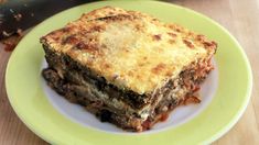 a green plate topped with lasagna on top of a wooden table