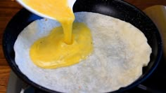 someone pouring sauce on top of an omelet in a skillet with a spatula