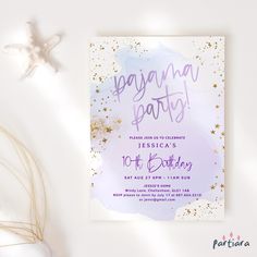 a purple and gold birthday party card on a white table with starfish, seashells and shells