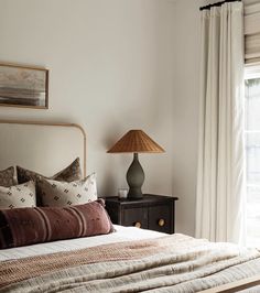 a bedroom with a bed, night stand and lamp in front of a large window