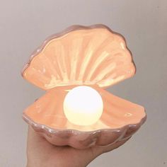 a hand holding a shell shaped candle holder