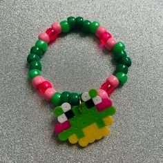 a bracelet made out of plastic beads with a green and pink bead on it