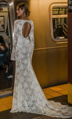 a woman in a white dress standing on a subway platform with her back to the camera