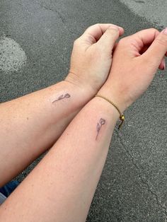 two people holding hands with tattoos on their wrists and wristbands, both showing the same