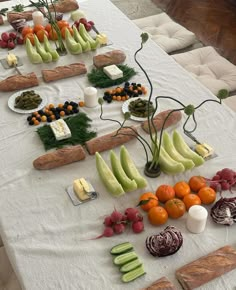 a table topped with fruits and vegetables on top of a white table cloth covered in food