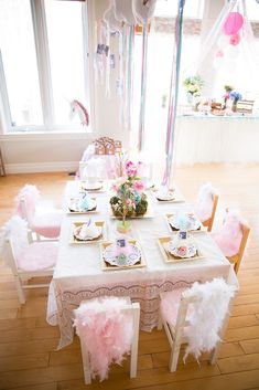 a table set up for a tea party with pink and blue decorations on the tables