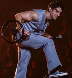 a man holding a steering wheel while standing on top of a car at a concert