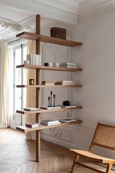 a wooden chair sitting next to a bookshelf on top of a hard wood floor