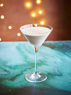 a glass filled with white liquid sitting on top of a green table next to lights