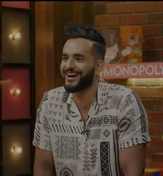 a man with a beard smiling in front of a brick wall