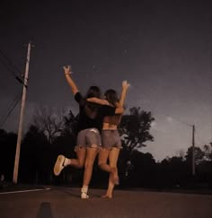 two girls jumping in the air with their arms around each other on a skateboard