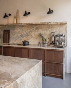 a kitchen with marble counter tops and wooden cabinets in the corner, along with potted plants