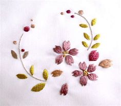 embroidered flowers and leaves are arranged in the shape of a circle on a white cloth