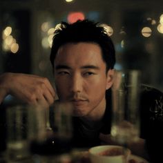 a man sitting at a table with cups in front of him