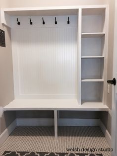 a white bench with shelves and hooks on the wall in a room that has tile flooring