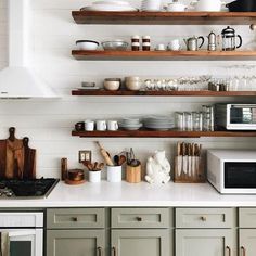 a kitchen filled with lots of open shelves next to a stove top oven and microwave