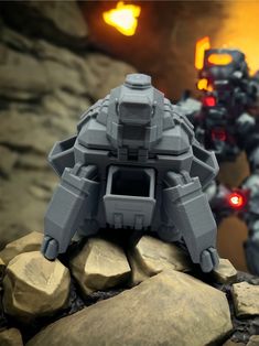 an action figure stands on top of rocks in front of a sci - fi robot