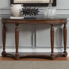 a table with two vases on top of it next to a painting and framed pictures