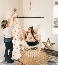 two women decorating a white christmas tree