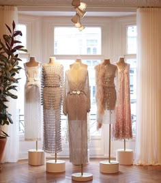 several mannequins and dresses on display in front of a window