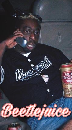 a man sitting in a car talking on a cell phone and holding a can of beer