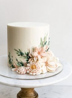 there is a white cake with flowers on the top and bottom, sitting on a marble platter