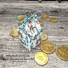 a small gift bag sitting on top of a wooden table filled with gold and silver coins