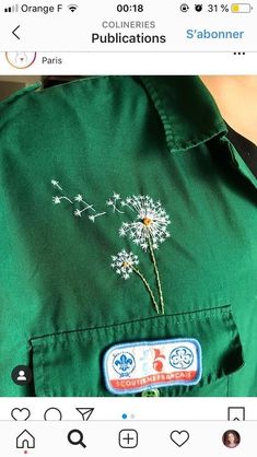 someone is wearing a green shirt with a dandelion embroidered on the front and back