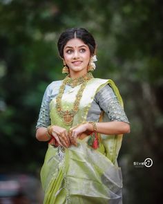 a woman in a green and white sari posing for the camera with her hand on her hip