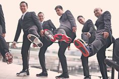 a group of men in suits and red shoes are posing for a photo with their feet up