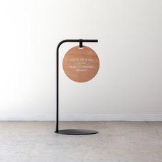 a wooden sign on a black metal stand in front of a white wall with the words grace of man quality assurance behind it