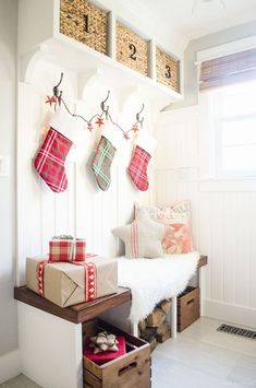 christmas stockings hung on the wall above a bench with presents under them and other holiday decorations