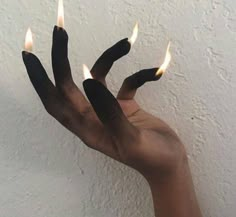 a person holding out their hand with three candles in it's palm, against a white wall