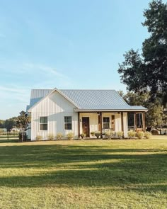 a white house sitting on top of a lush green field next to a tree and grass covered field