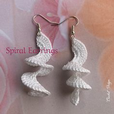 crochet earrings with white flowers and silver hooks are shown in front of a floral background