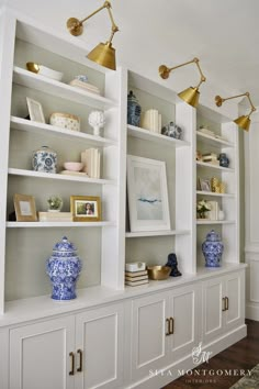 a white bookcase with blue and white vases on the front, and gold accents on the back