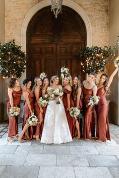 a group of women standing next to each other in front of a door holding bouquets