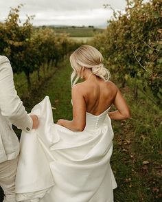 a bride and groom walking through an orchard