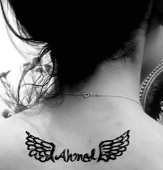 the back of a woman's neck with an angel wing tattoo