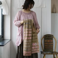 a woman standing in front of a chair holding onto a piece of cloth that is hanging on the wall