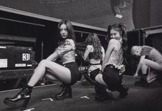 three women in short skirts and boots are posing for a black and white photo,