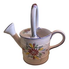 a ceramic tea pot with two spoons sticking out of it's top and bottom