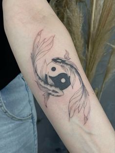 a woman's arm with a black and white koi fish tattoo on it