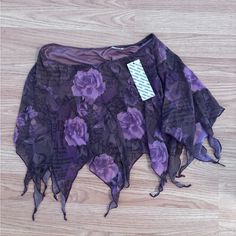 a purple and black flowered skirt on a wooden floor with a tag attached to it