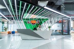 an office lobby with white tile flooring and neon lights on the ceiling, as well as a sculpture